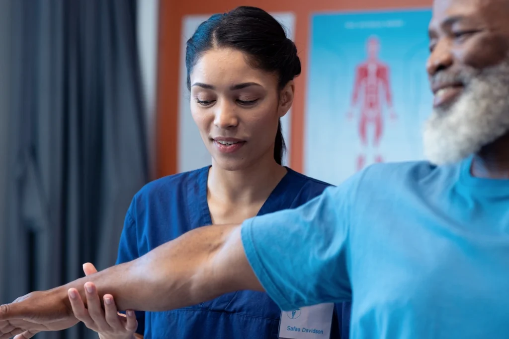 diverse-female-physiotherapist-treating-arm-of-sen-2023-11-27-05-25-37-utc